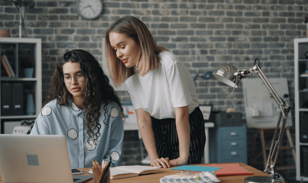 Two colleagues looking at an applicant tracking system on a laptop screen.